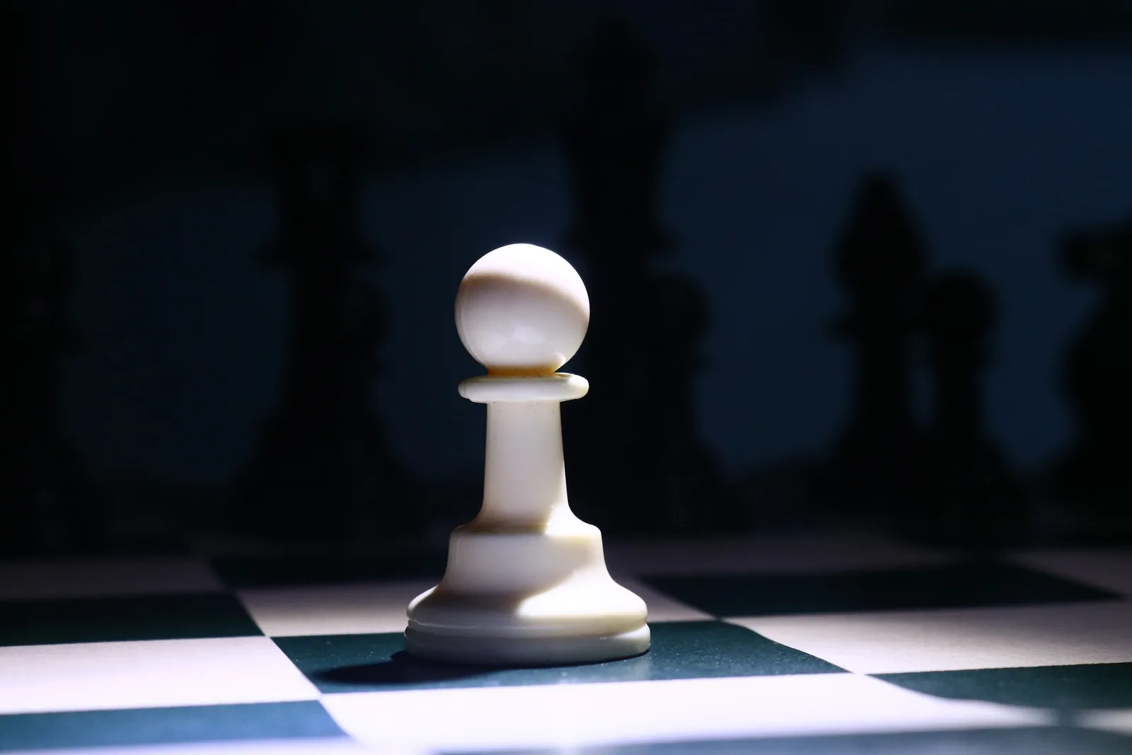 Close-up of a white chess pawn highlighted dramatically on a chessboard, depicting strategy and focus.